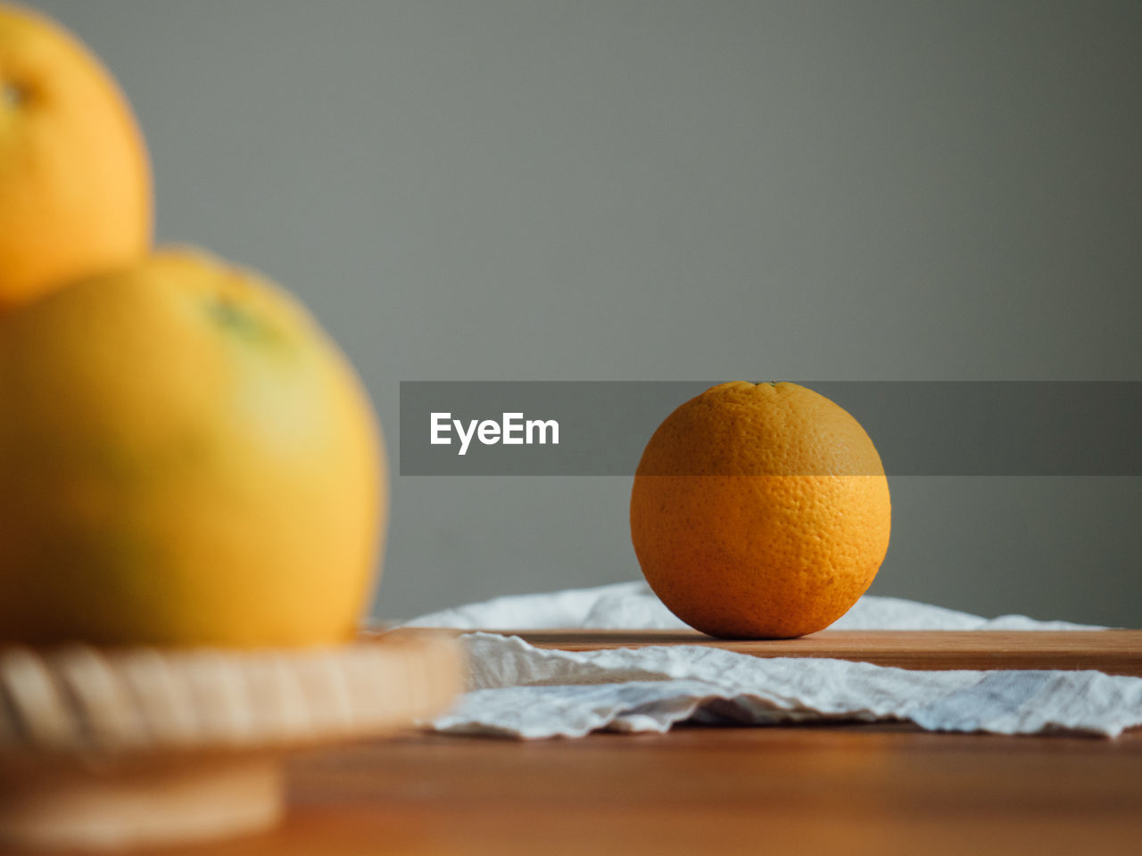 CLOSE-UP OF ORANGE FRUIT ON TABLE AGAINST GRAY BACKGROUND