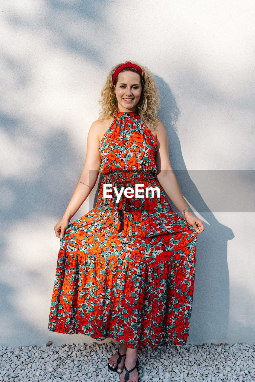 Portrait of smiling young woman standing against blurred background