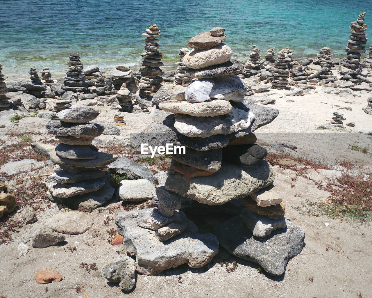water, rock, beach, sea, balance, land, nature, zen-like, stone, day, tranquility, shore, sunlight, coast, beauty in nature, pebble, no people, tranquil scene, high angle view, outdoors, sand, scenics - nature, large group of objects, geology