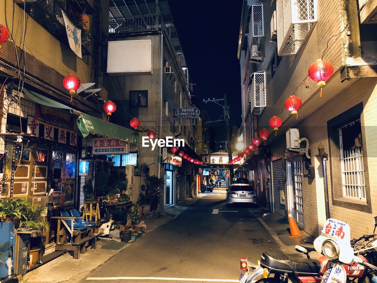 Illuminated street amidst buildings in city at night