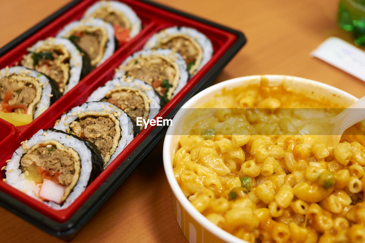 High angle view of gimbap with macaroni and cheese on table