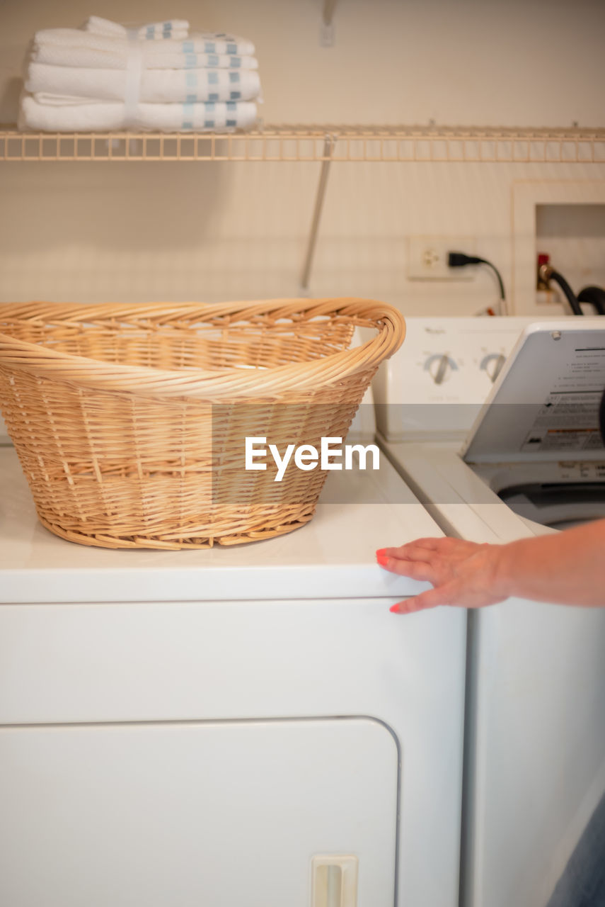 Cropped hand of woman using washing machine in home