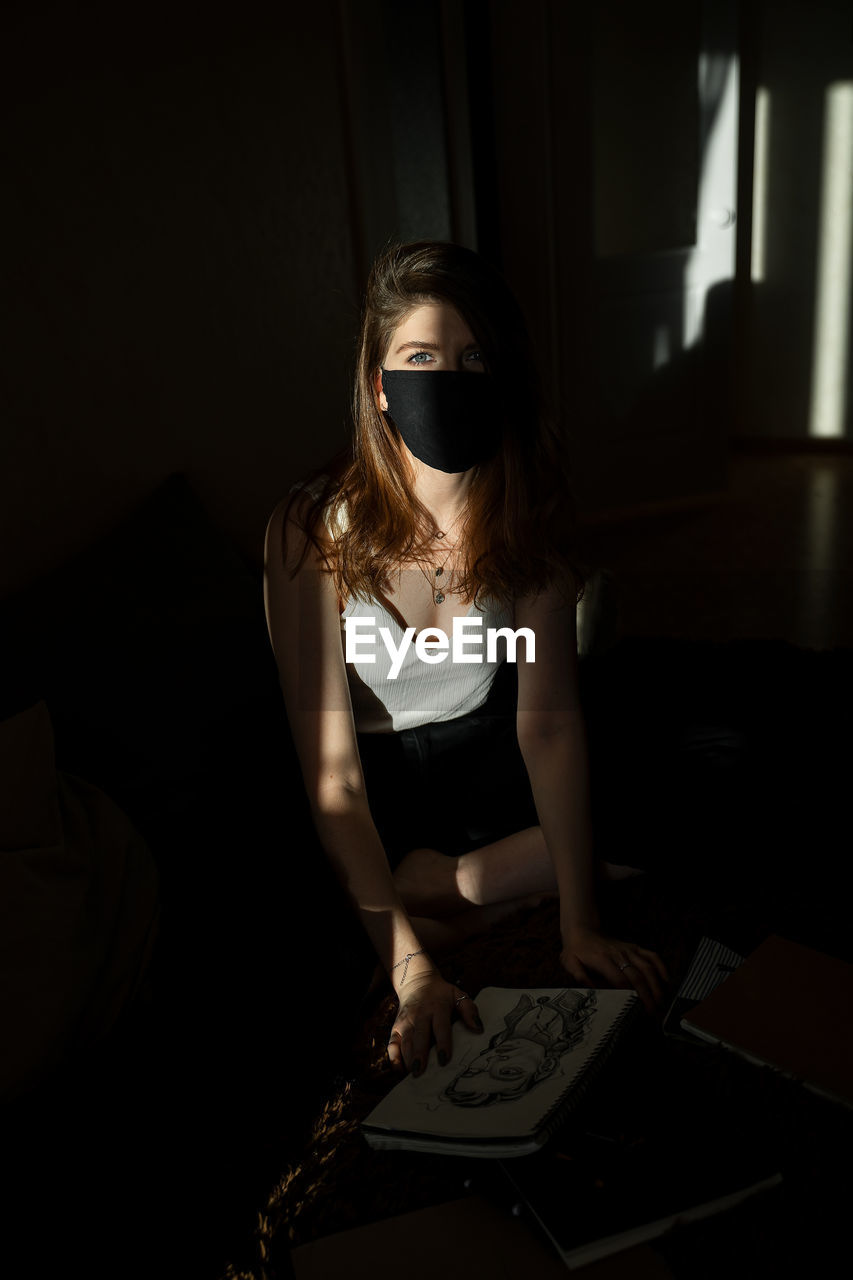Portrait of woman wearing mask in darkroom