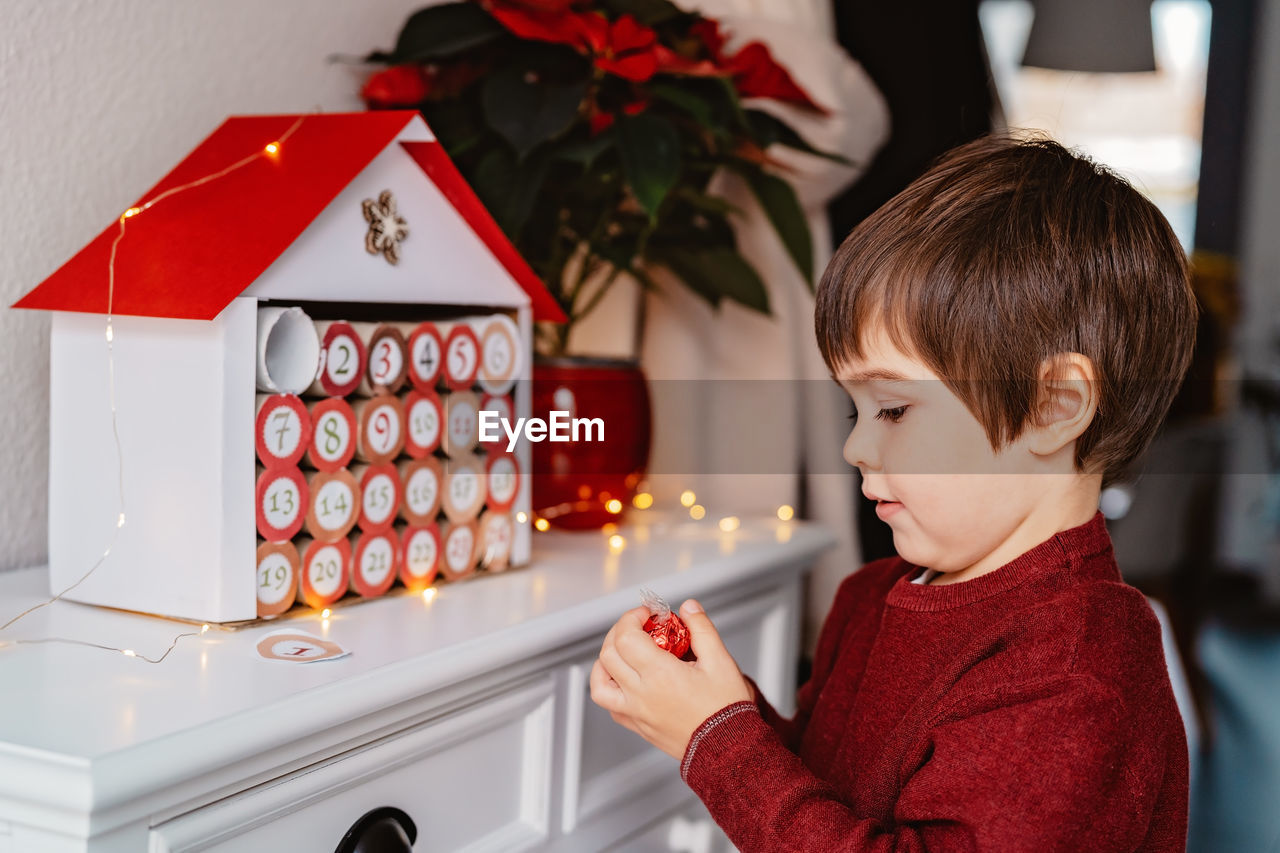 Child taking chocolate opening first gift in handmade advent calendar. sustainable christmas,.