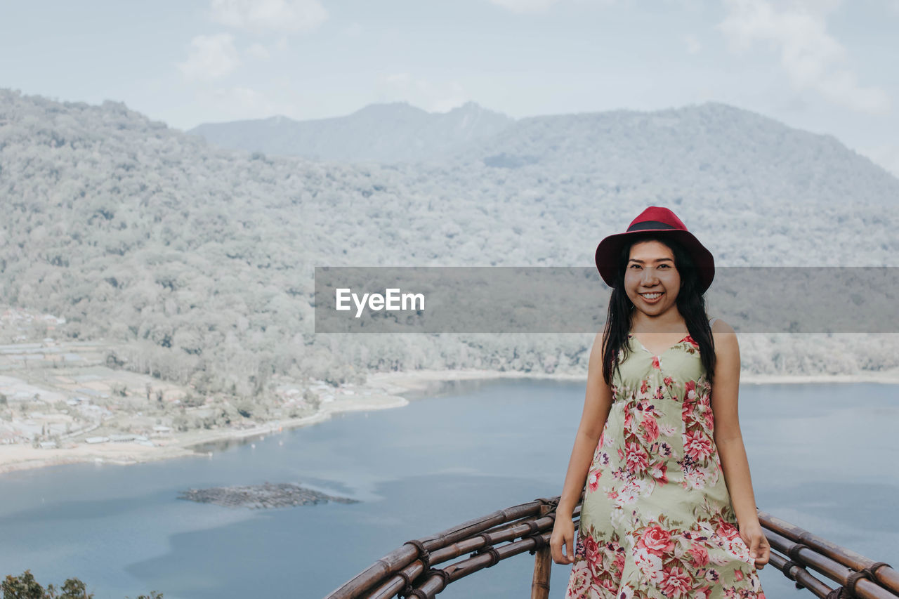 Portrait of young woman standing against mountain