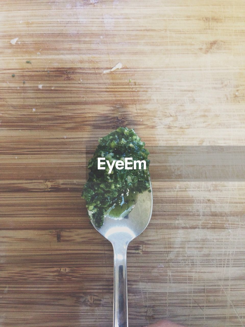 Close-up of spoon filled with basil pesto on wooden table