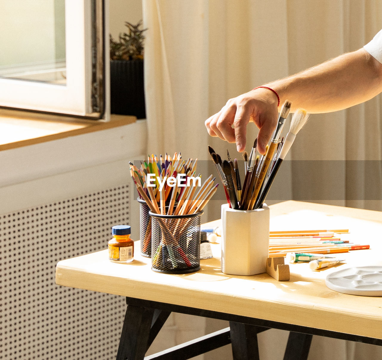 Midsection of men holding paintbrushes on table at home