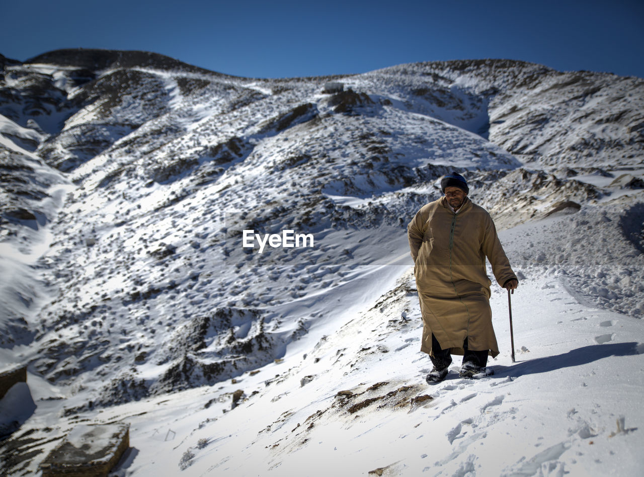 Full length of man standing on snow covered mountain