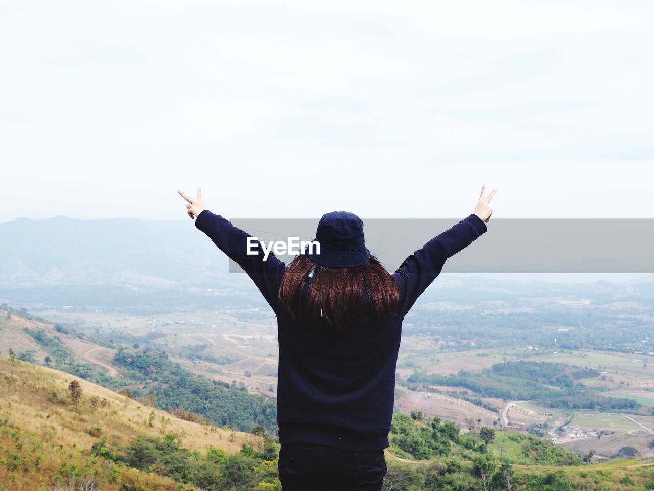 Rear view of woman with arms outstretched standing on landscape