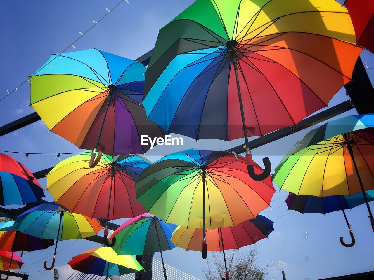 LOW ANGLE VIEW OF UMBRELLAS AGAINST BLUE SKY