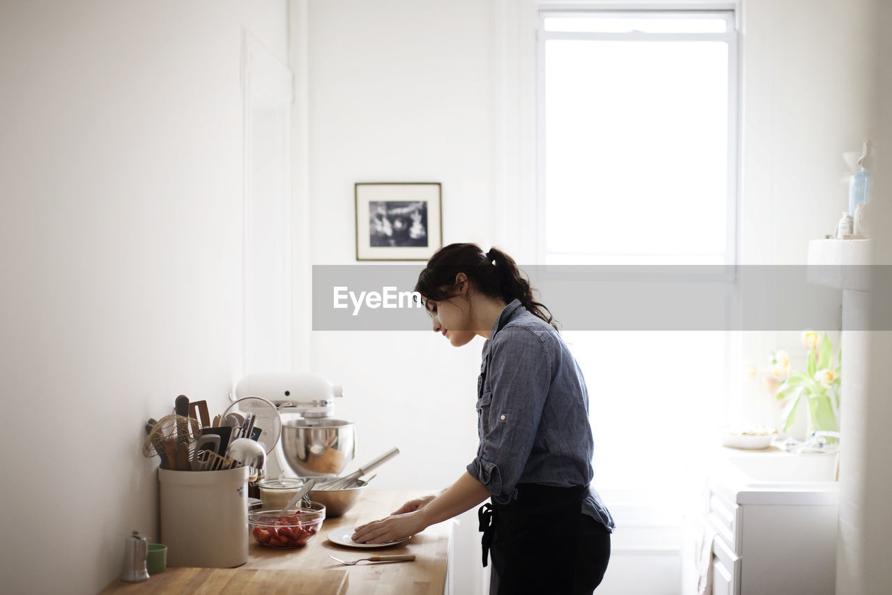 Side view of woman preparing food at home