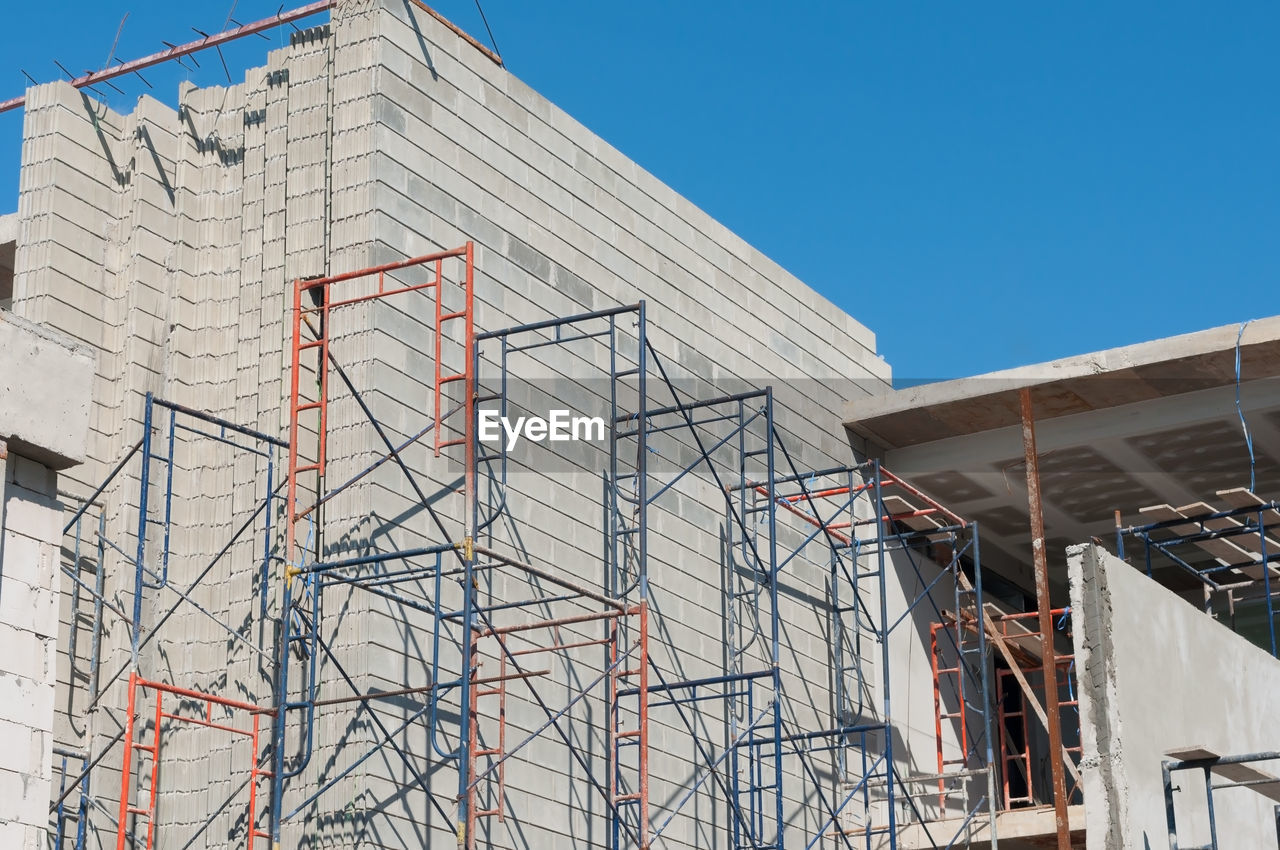 LOW ANGLE VIEW OF BUILDING UNDER CONSTRUCTION AGAINST BLUE SKY