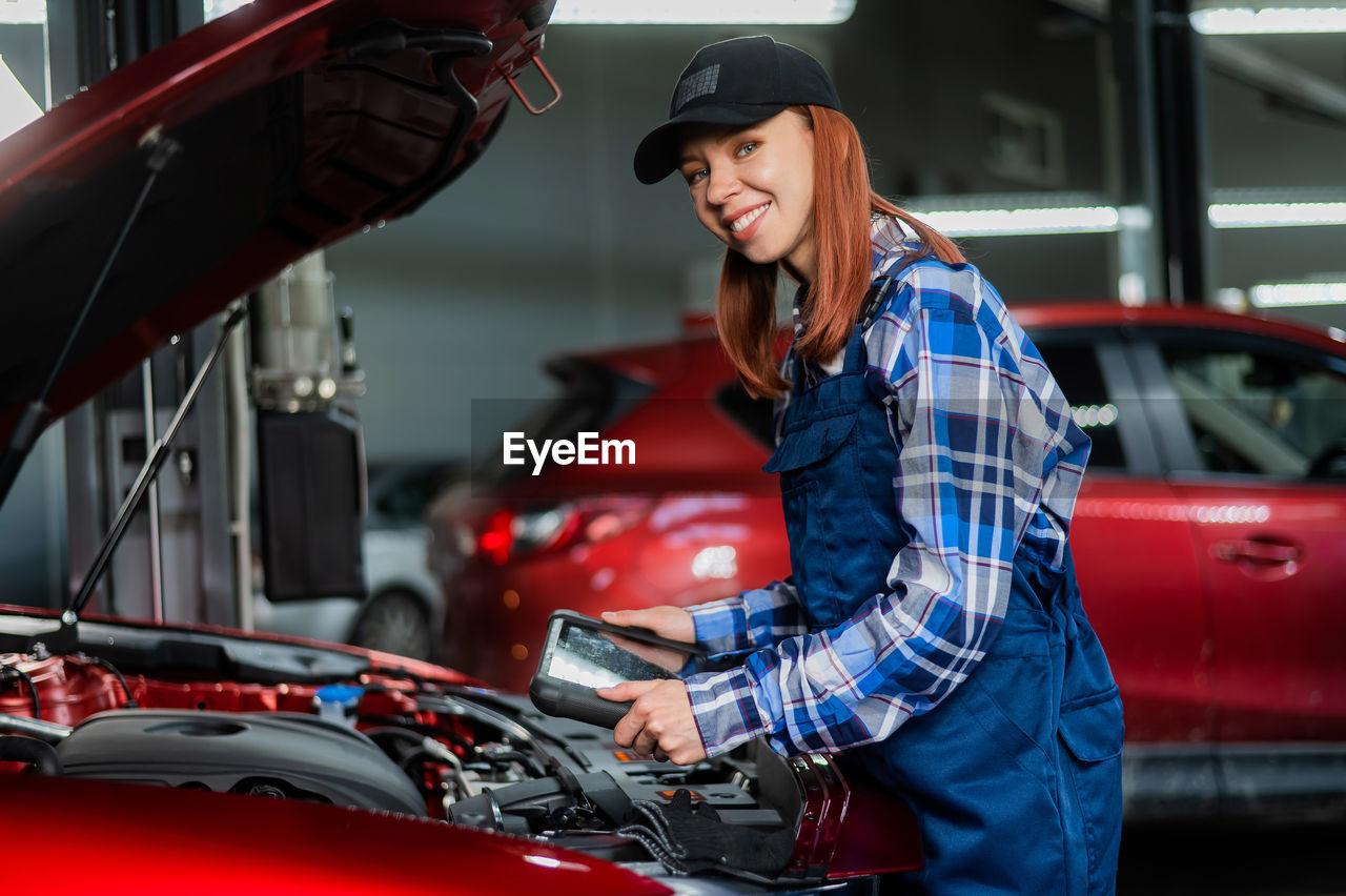 Caucasian female auto mechanic uses a special computer to diagnose faults