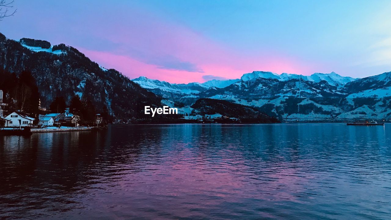 Scenic view of lake and mountains against sky during sunset