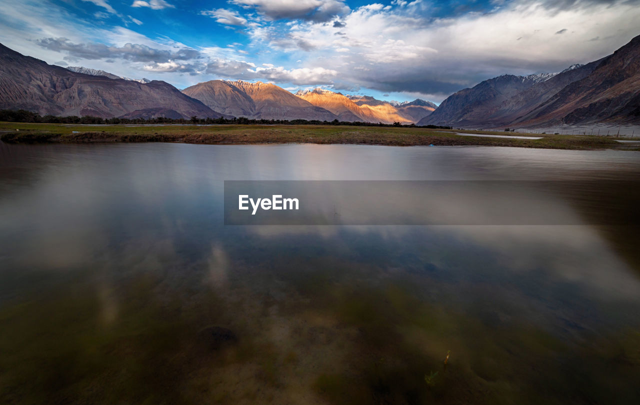 Scenic view of lake by mountains against sky