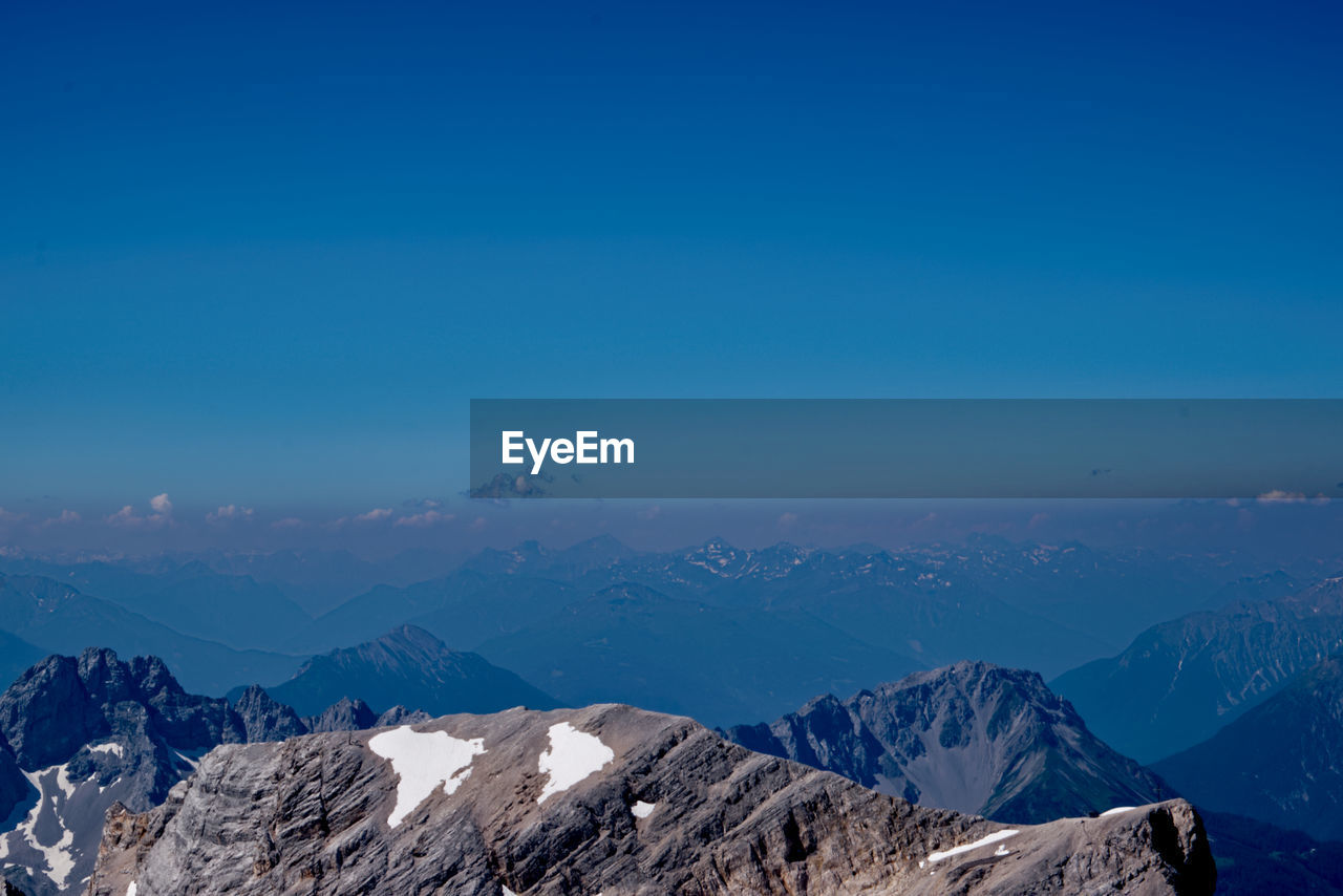 Scenic view of snowcapped mountains against blue sky