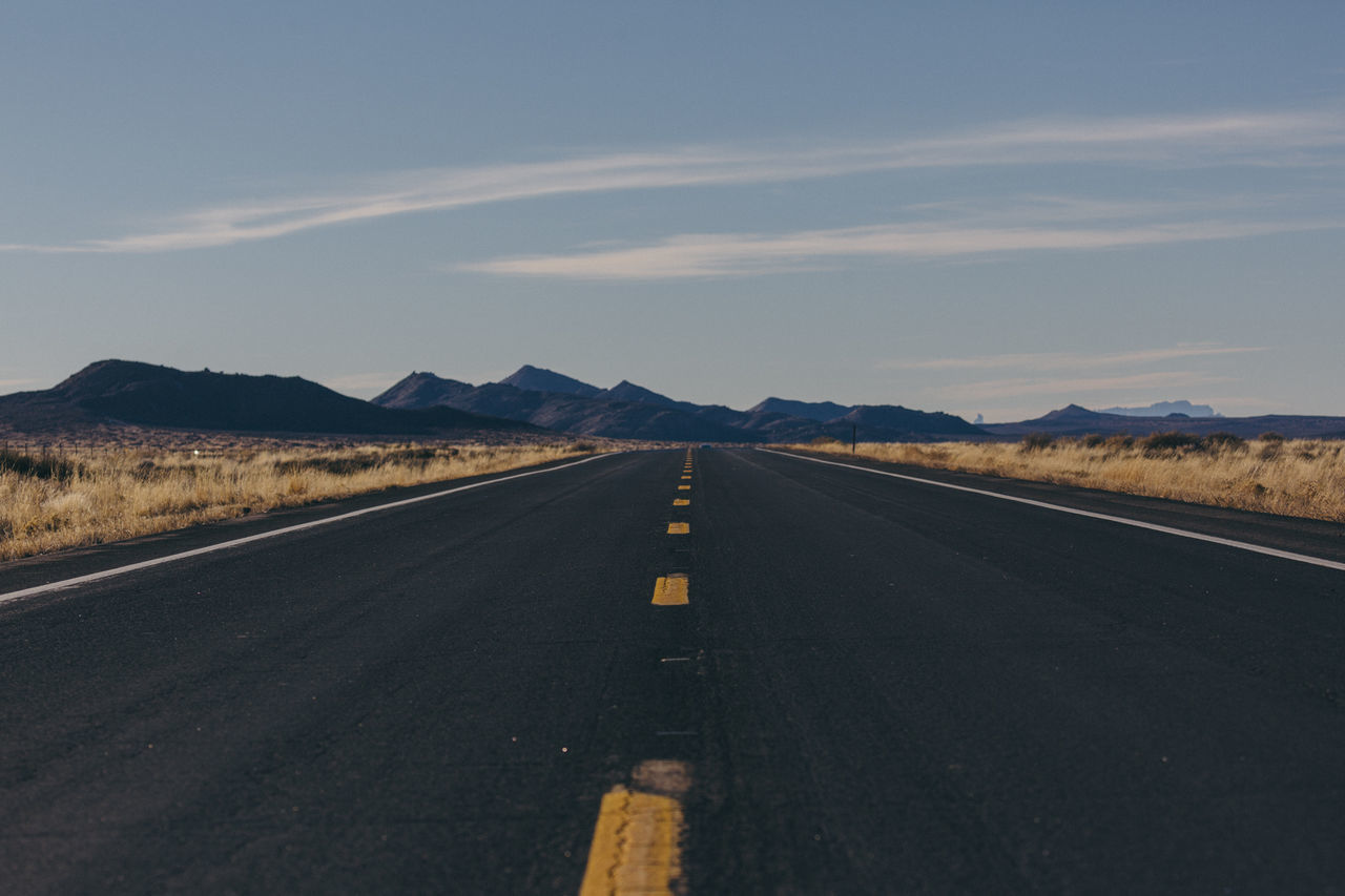 Scenic view of road amidst field against sky