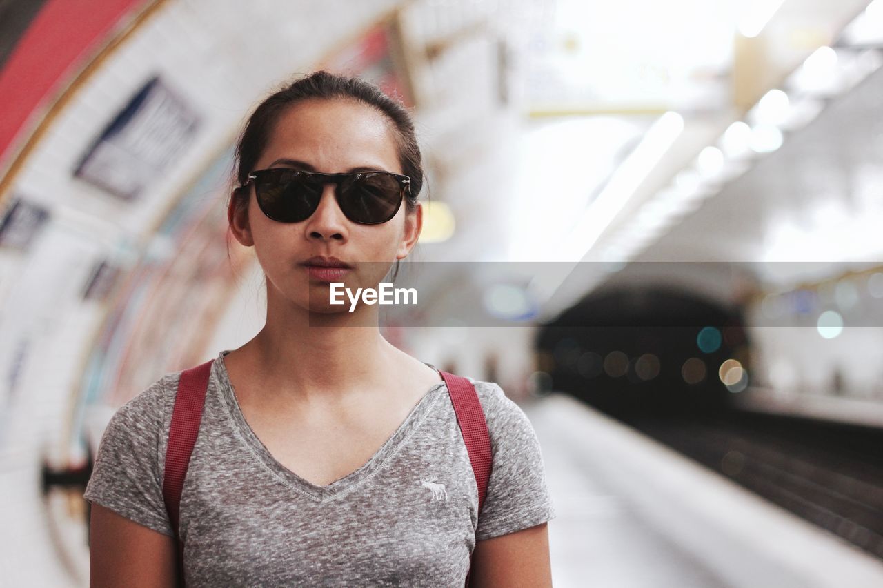 Portrait of young woman wearing sunglasses at subway station