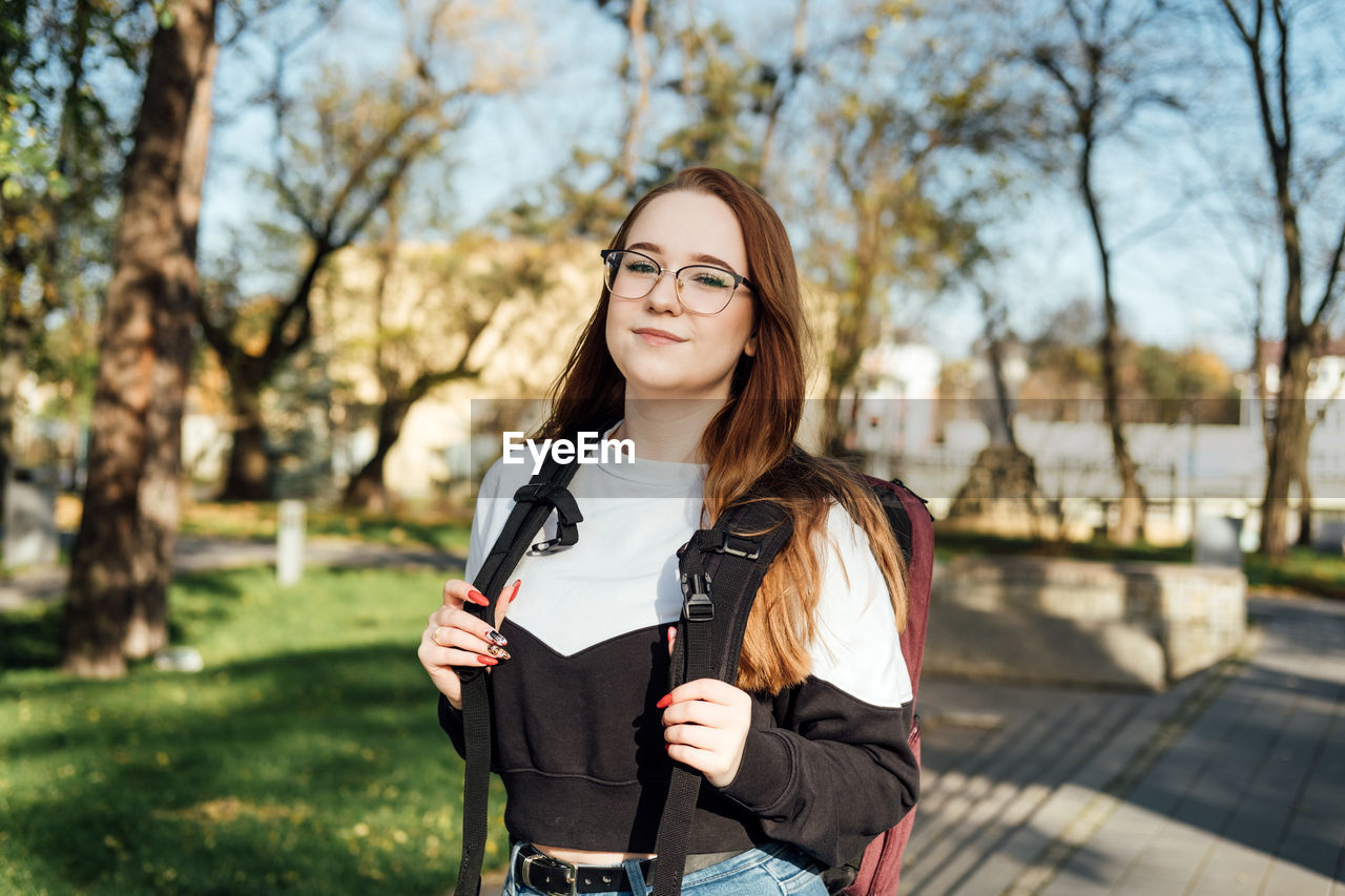 Choosing a university, college. female college student with books and laptop outdoors. redhead