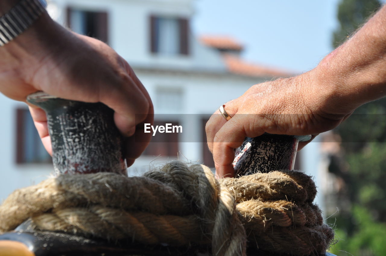 Close-up of human hands on moored rope