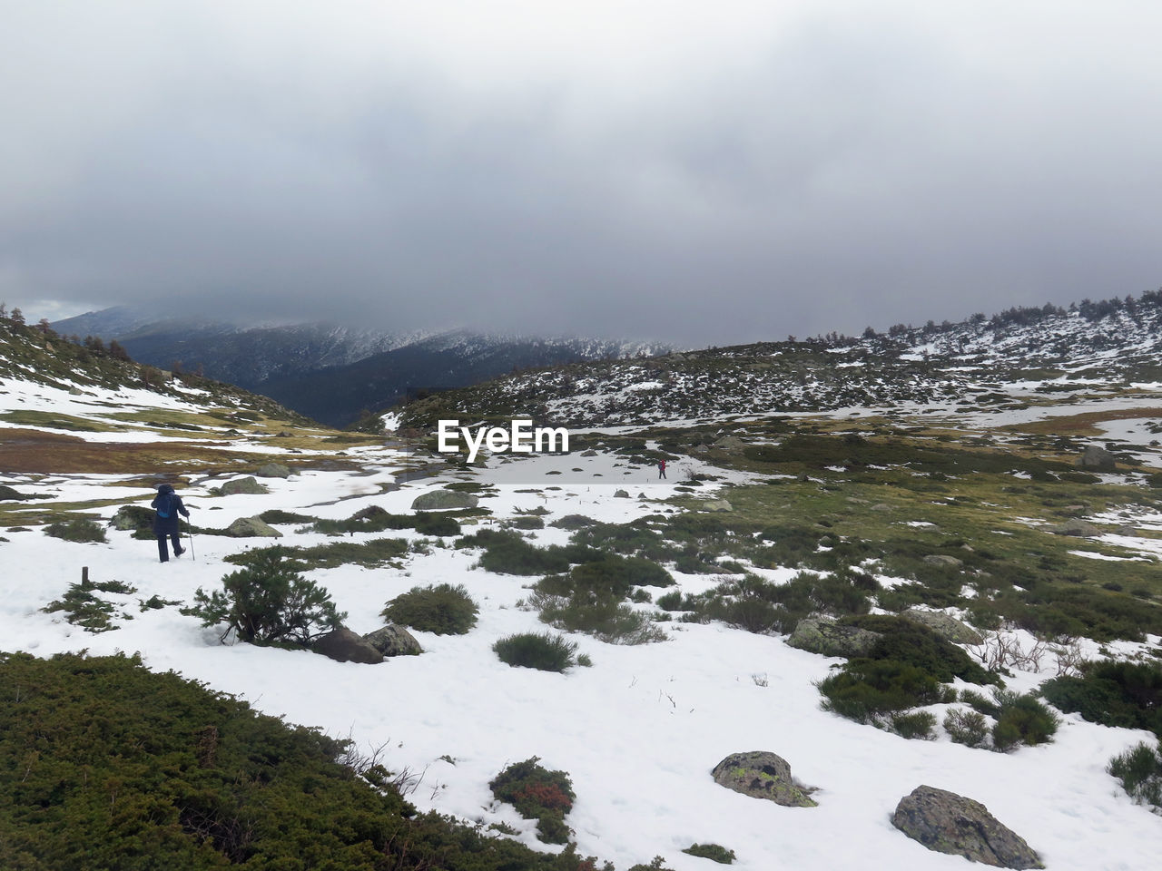 Man walking on snow covered land against sky