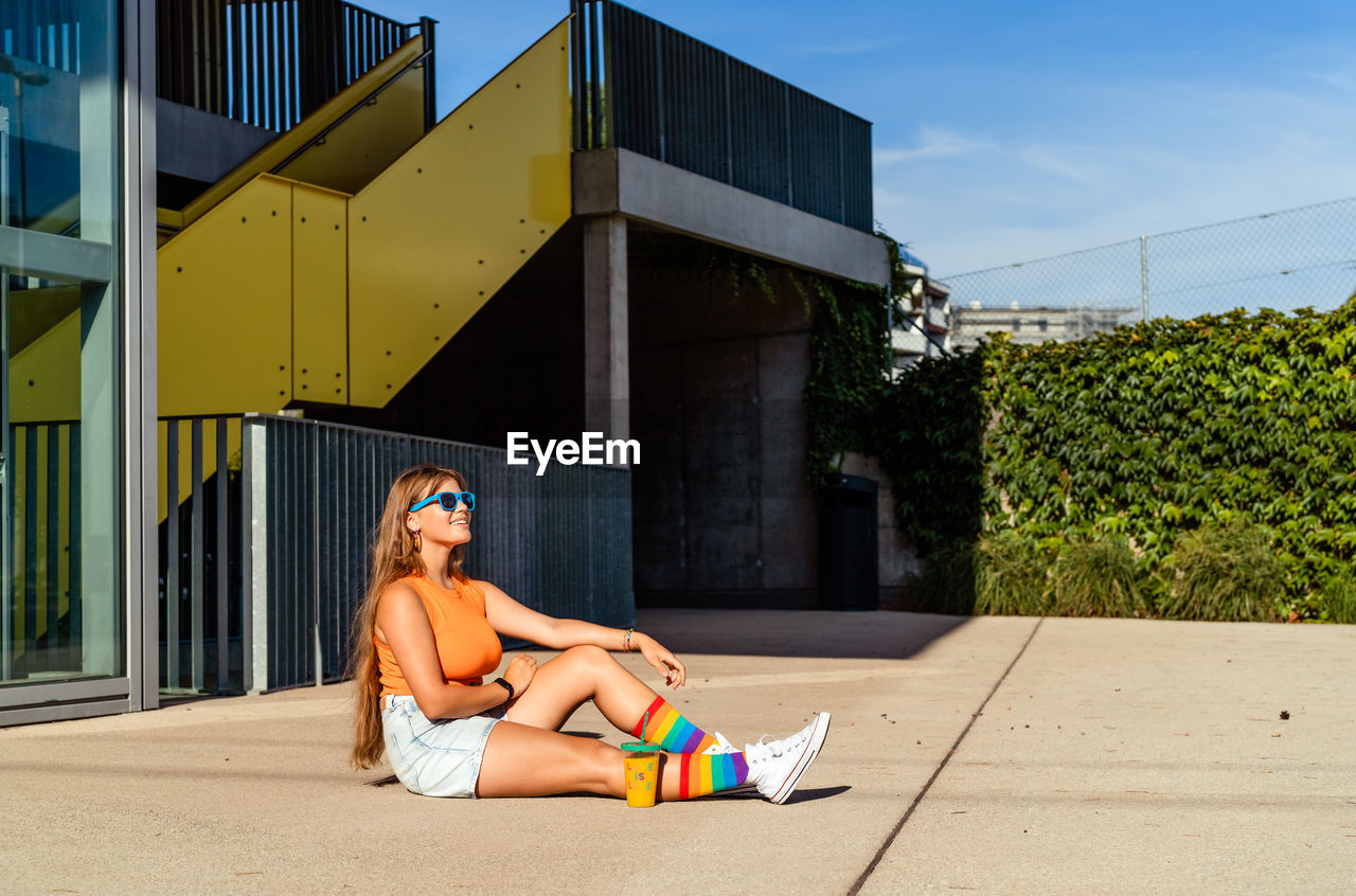 Young happy smiling teen girl wearing bright colorful top and rainbow pride socks enjoying sun 