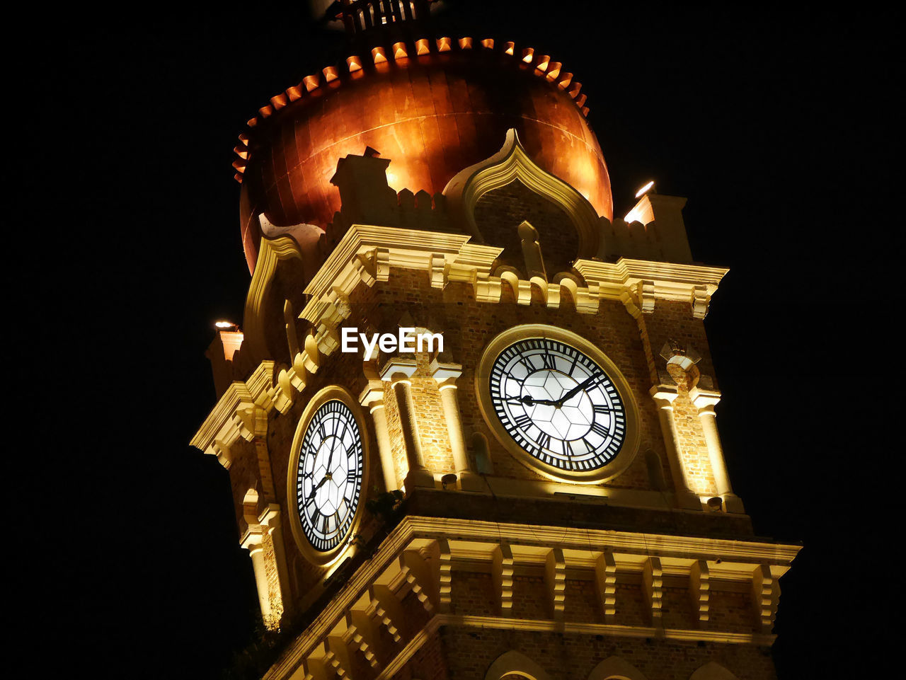 LOW ANGLE VIEW OF CLOCK TOWER AGAINST ILLUMINATED BUILDING