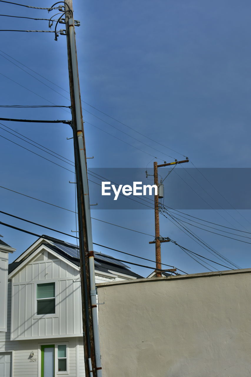 Low angle view of electricity pylons and buildings against sky