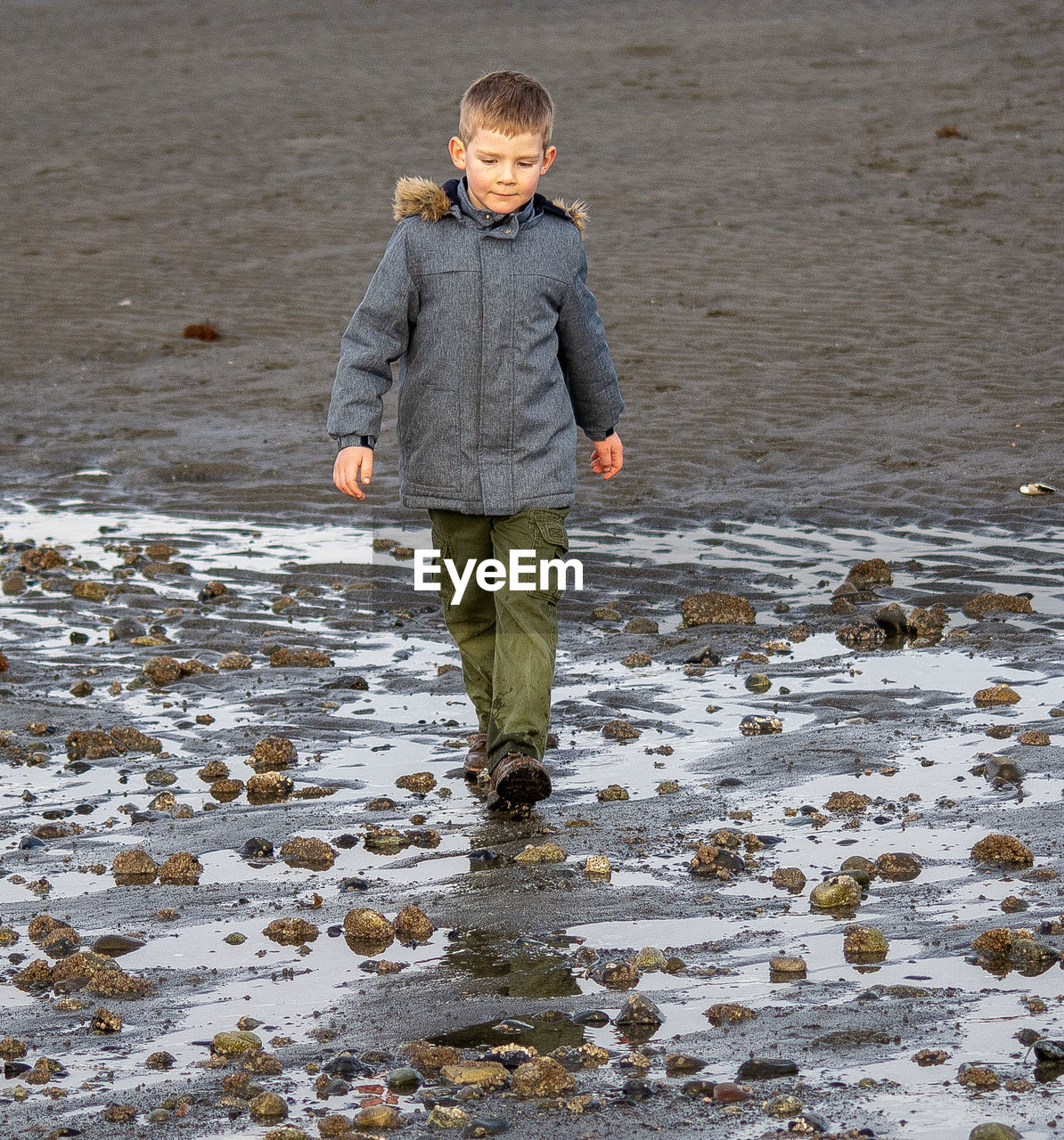 Boy walking at wet beach