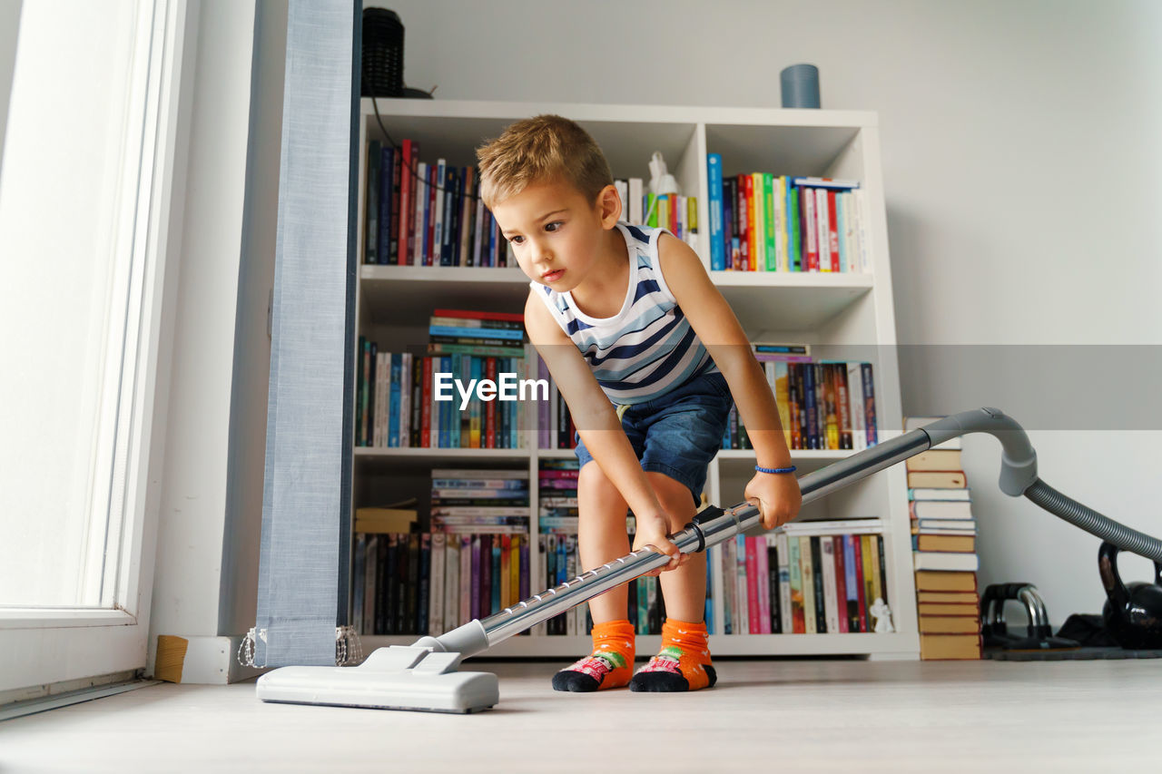 BOY STANDING IN SHELF AT HOME