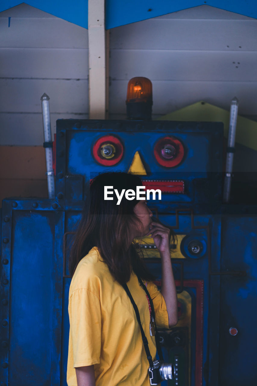 Side view of woman looking away while standing by robot