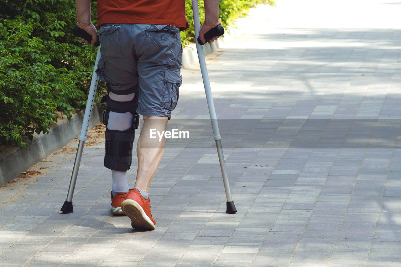 LOW SECTION OF WOMAN WALKING ON FOOTPATH