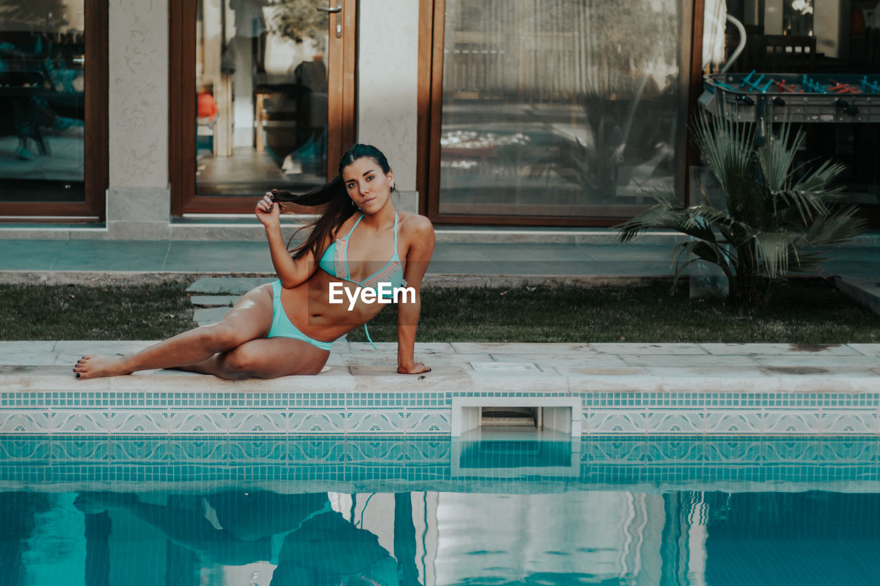 WOMAN SITTING ON SWIMMING POOL