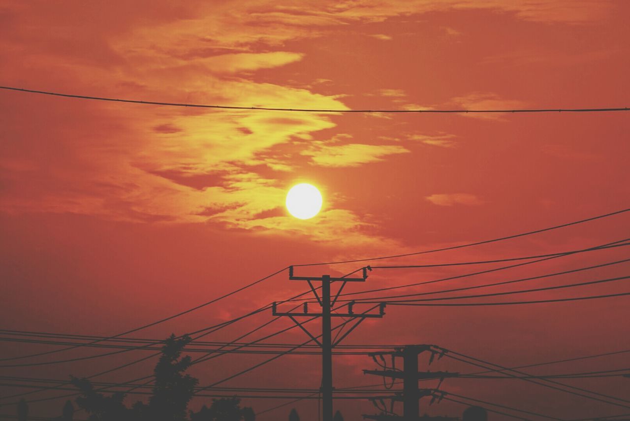 Silhouette electricity pylon and cable against orange sky during sunset