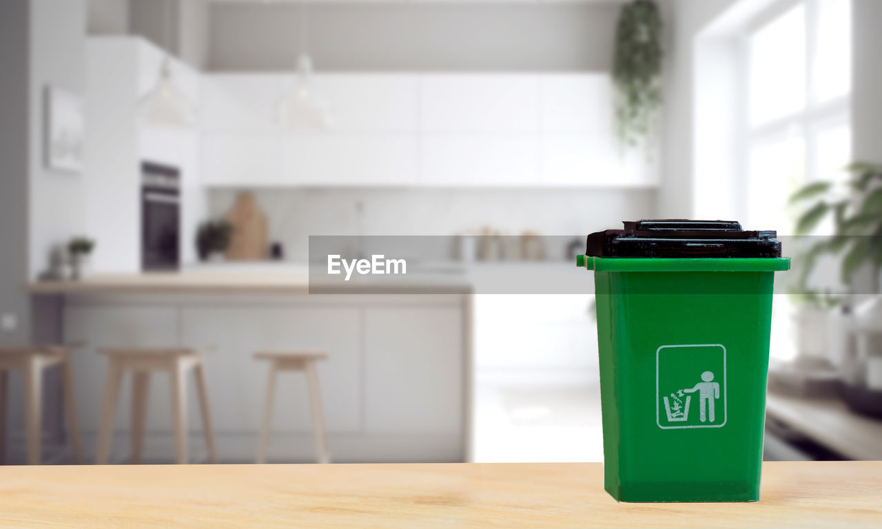 indoors, waste container, table, green, environmental conservation, furniture, garbage bin, environmental issues, no people, focus on foreground, recycling, domestic room, lighting, home interior, environment, domestic life, day, container, communication, flowerpot, nature, desk