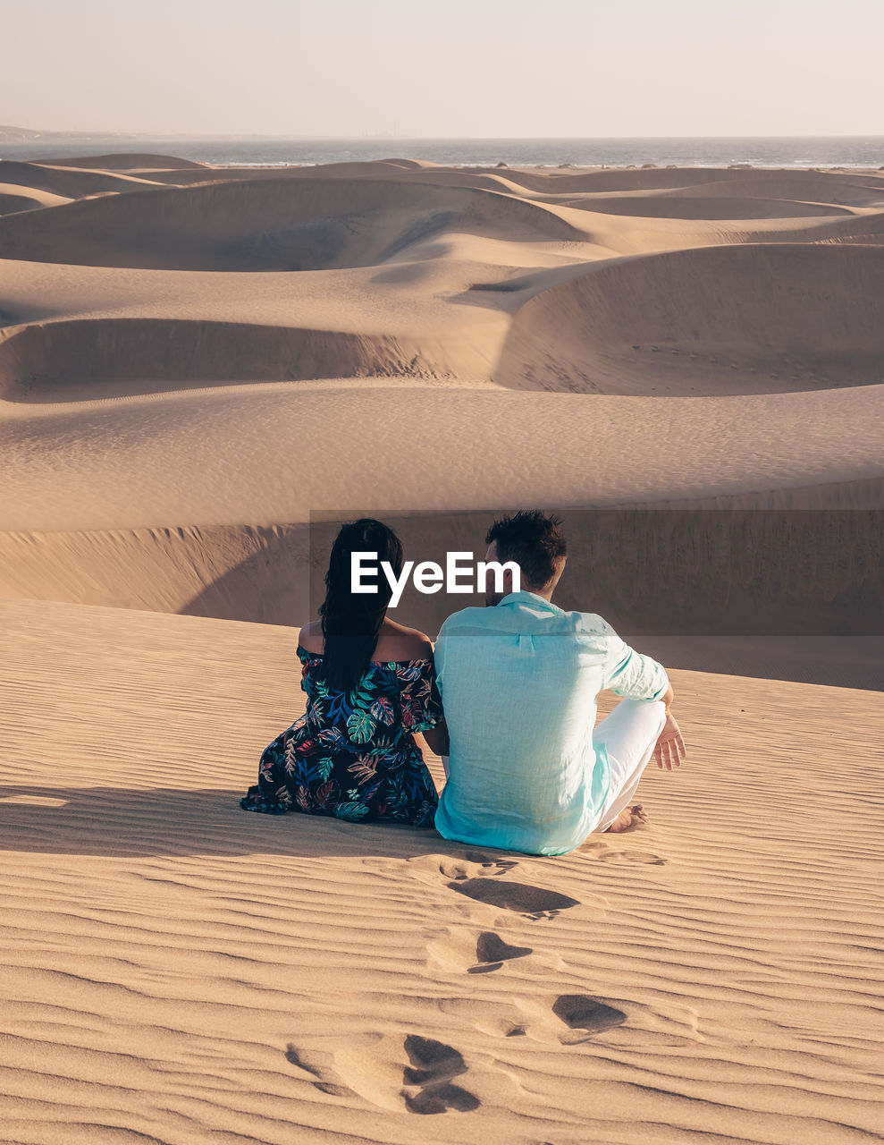 rear view of man sitting on sand at beach