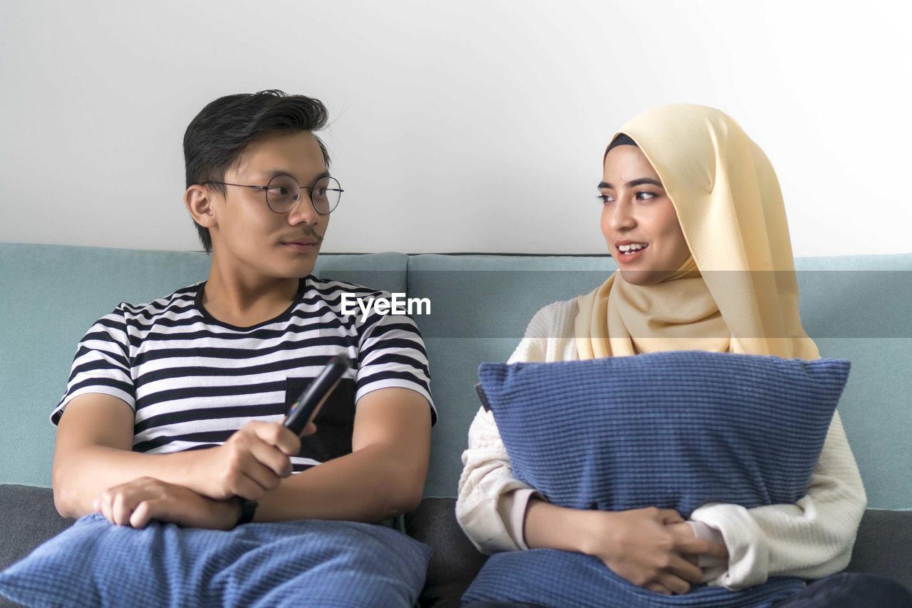 YOUNG COUPLE SITTING IN FRONT OF TWO PEOPLE
