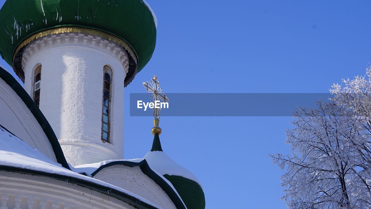 Low angle view of religious cross on building against clear blue sky