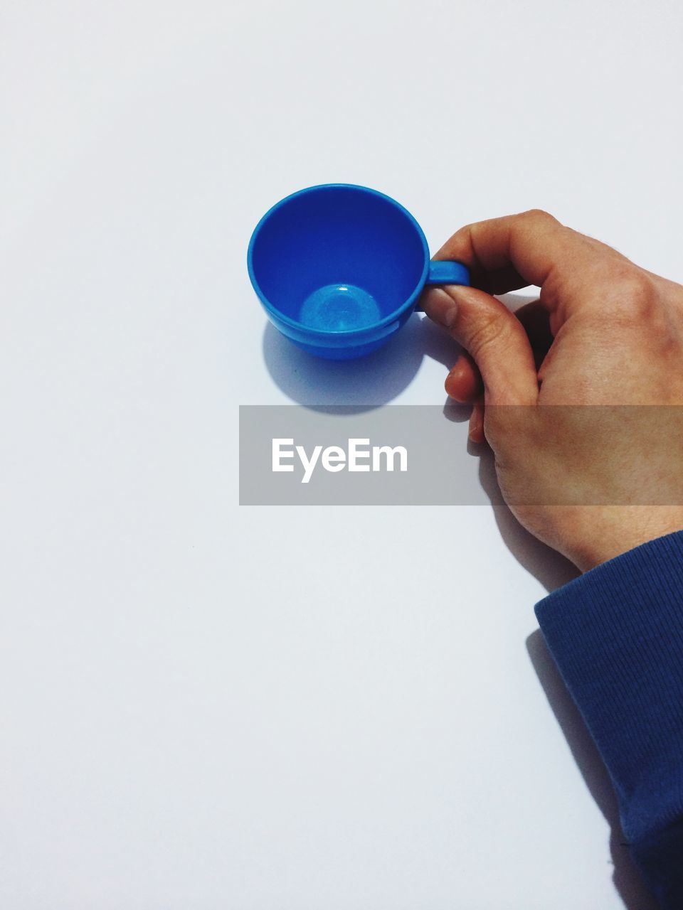 Cropped image of man holding toy tea cup against white background