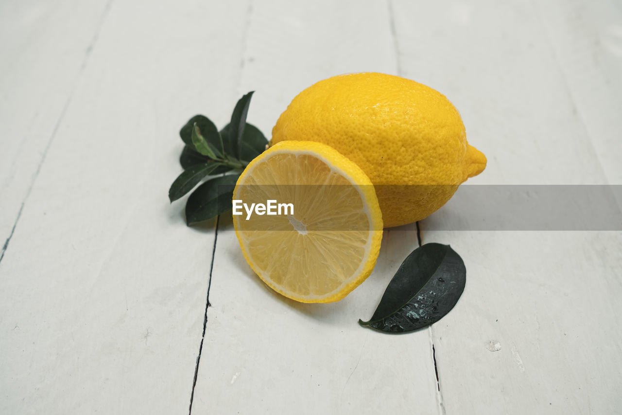 Lemons with leaves on wooden background