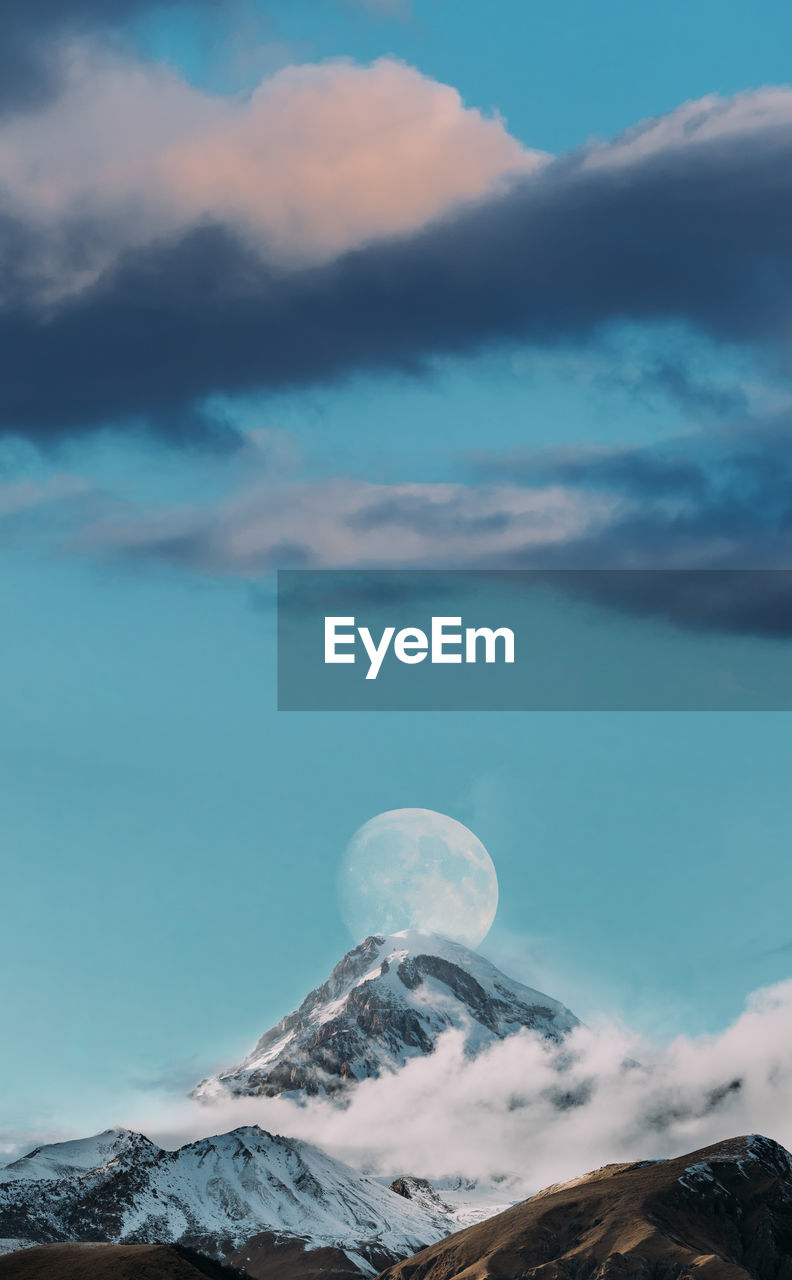 low angle view of snowcapped mountains against cloudy sky