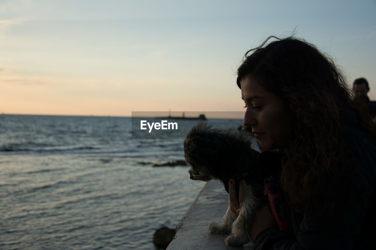 CLOSE-UP OF YOUNG WOMAN AT BEACH AGAINST SKY