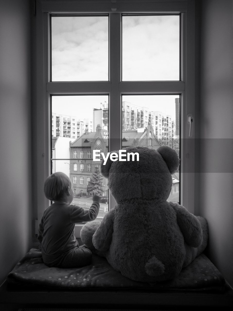 Rear view of boy with stuffed toy sitting at home