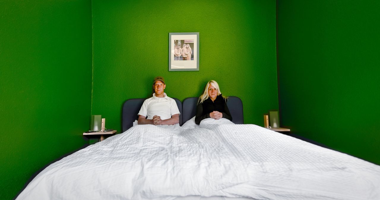 Portrait of couple praying while sitting on bed in green room