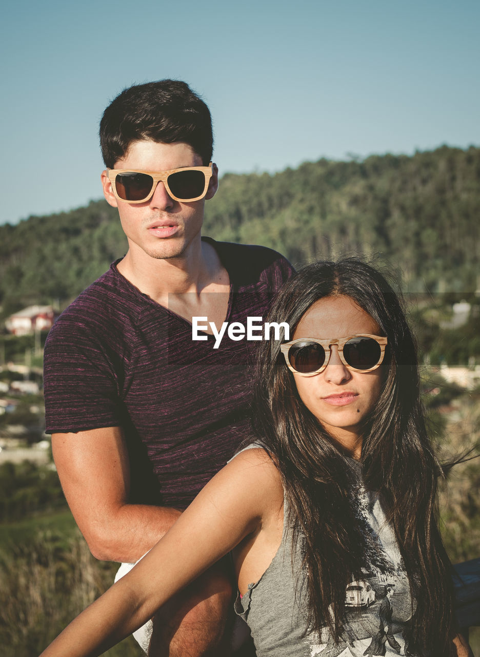 Young couple wearing sunglasses against sky