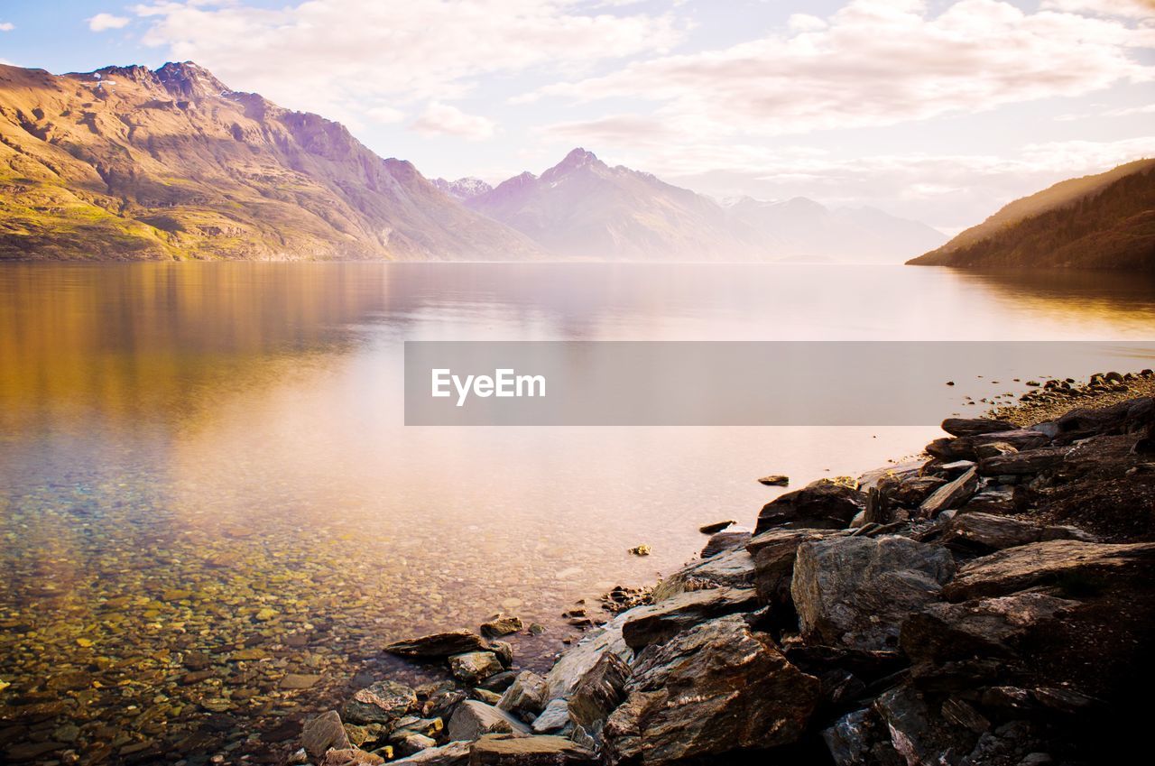 Lake with mountains in background at sunset