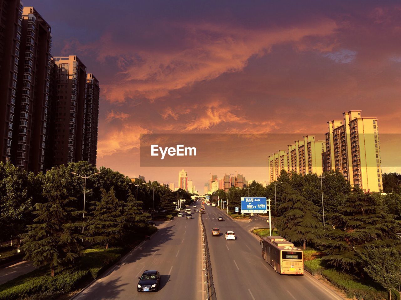 High angle view of vehicles moving on city street against cloudy sky during sunset