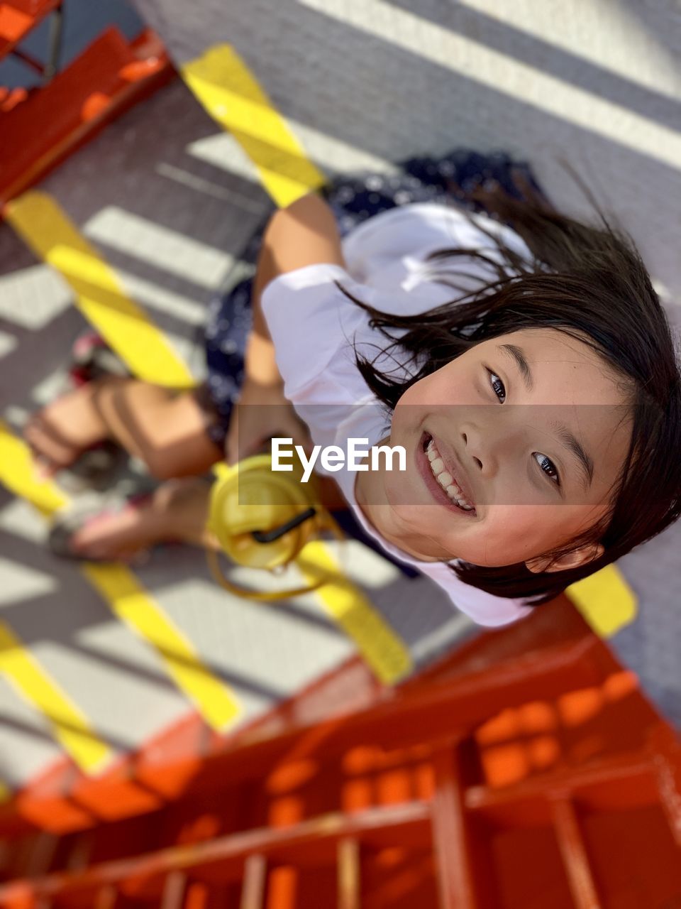 High angle portrait of cute girl sitting in playground