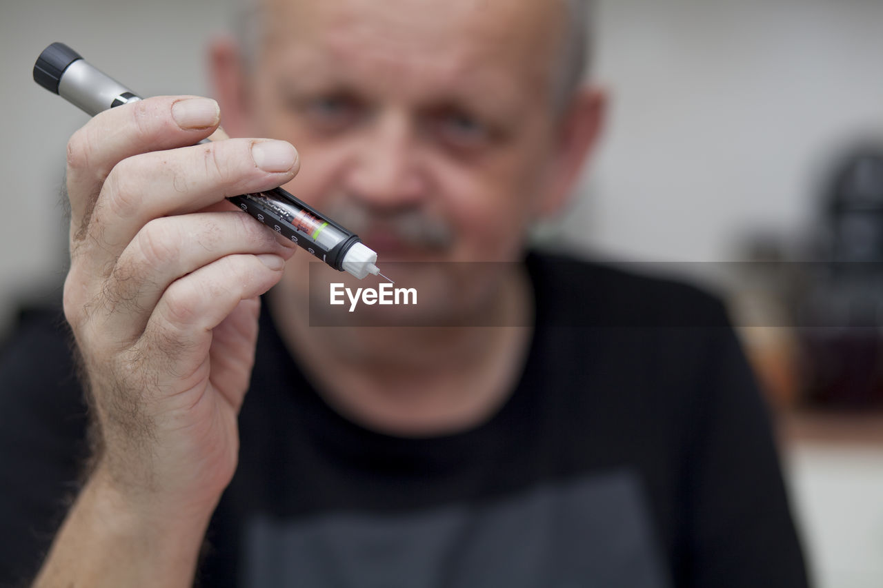 Close-up of mature man holding insulin equipment