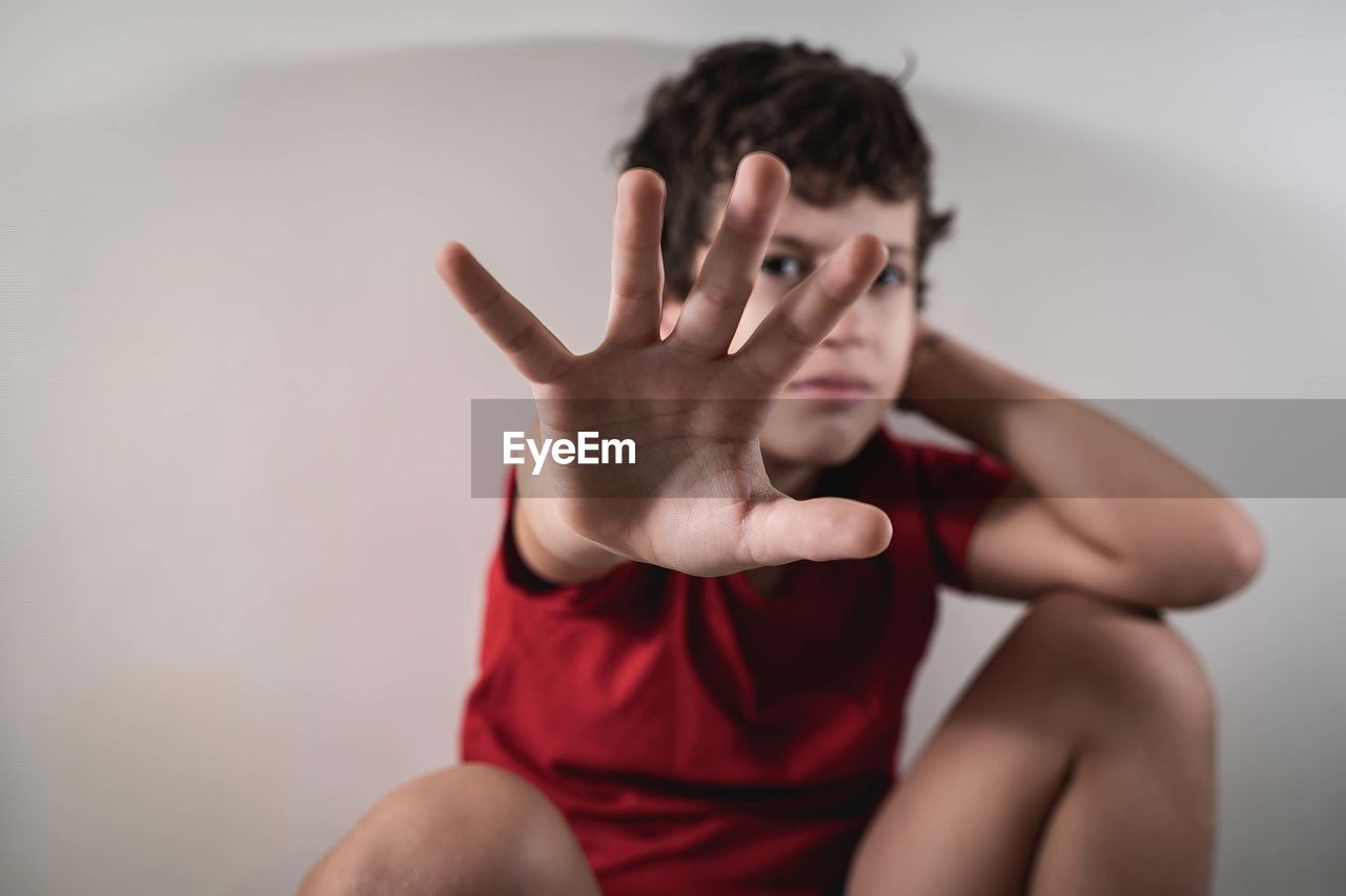 Kid hiding face with his hand asking to stop violence. no violence against children concept.